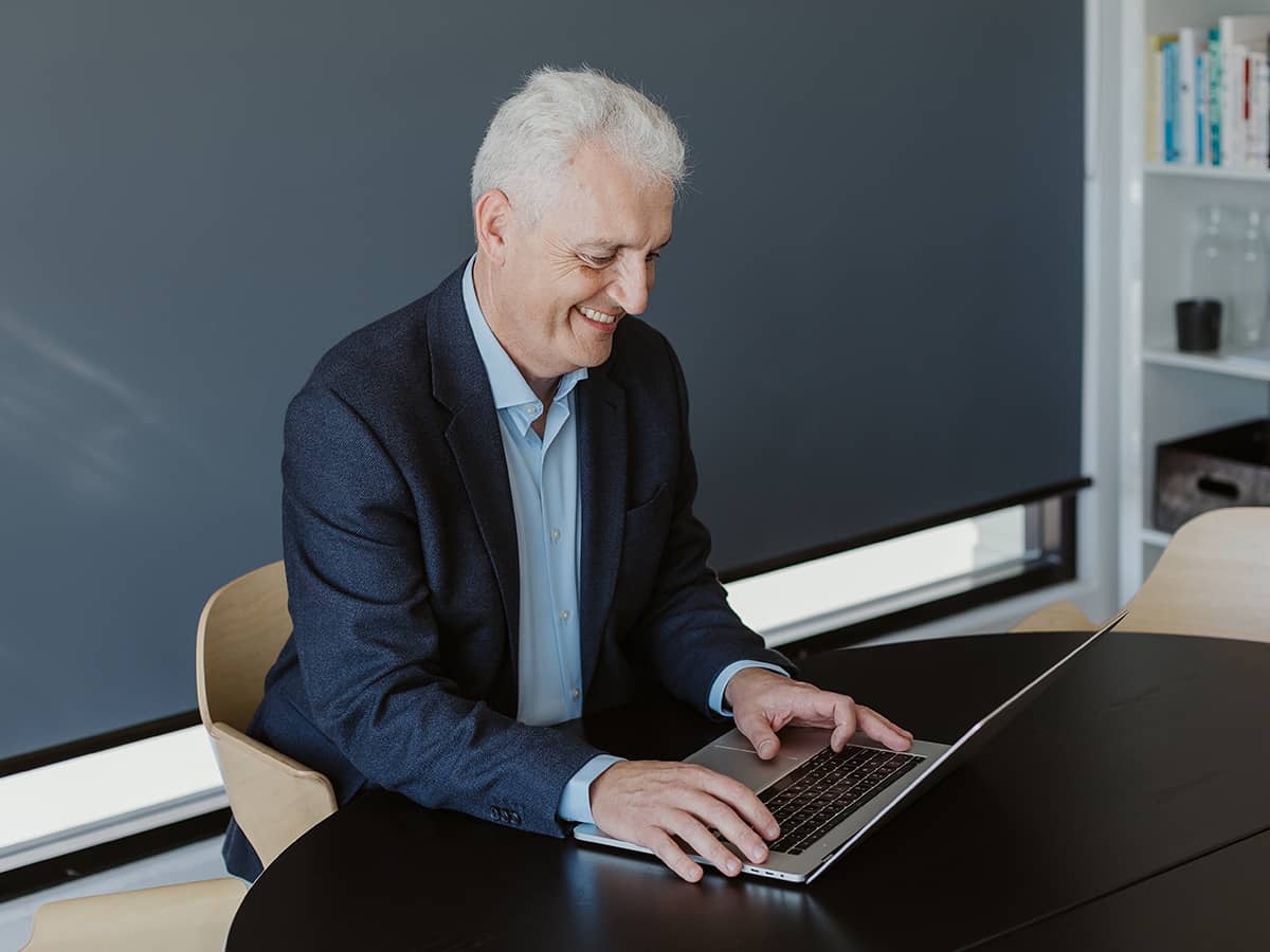 Chris Cooper working on laptop at modern office desk.